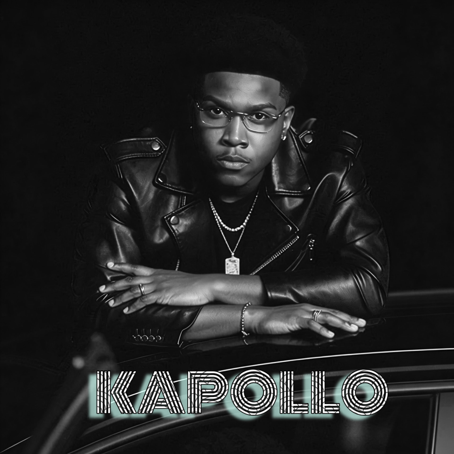 KAPOLLO in a black leather jacket leaning on a car at night, monochrome portrait with the KAPOLLO wordmark below.